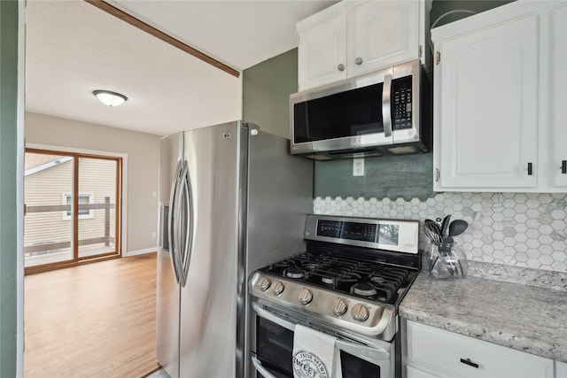 330 E 13th St N, Newton, IA 50208 - kitchen featuring appliances with stainless steel finishes, white cabinetry, tasteful backsplash, and light wood-type flooring