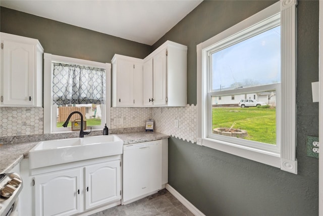 330 E 13th St N, Newton, IA 50208 - kitchen featuring white dishwasher, a sink, decorative backsplash, and white cabinetry