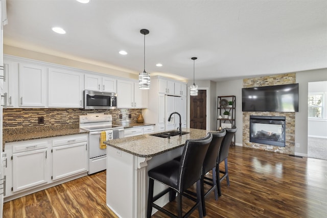 kitchen with white electric range oven, stainless steel microwave, a sink, dark wood-style flooring, and white cabinets