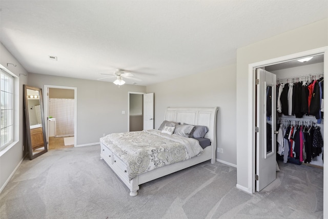 bedroom with a walk in closet, light carpet, baseboards, and a closet