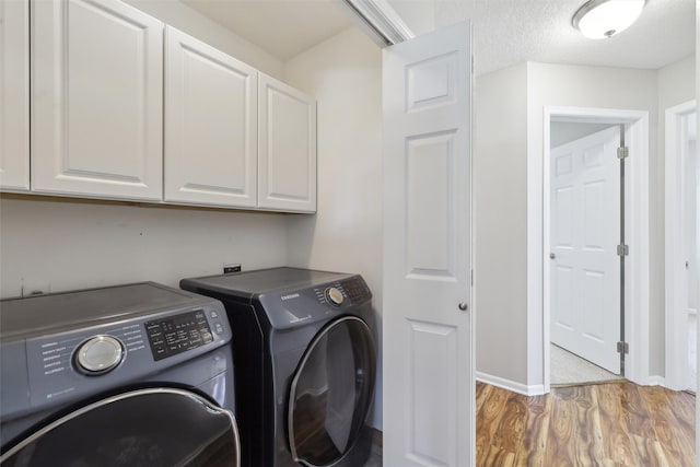 laundry room featuring cabinet space, washing machine and dryer, light wood finished floors, and baseboards