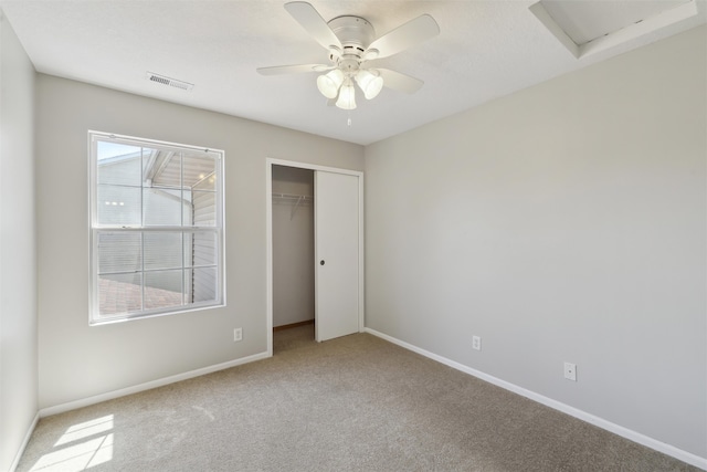 unfurnished bedroom with carpet flooring, baseboards, a closet, a ceiling fan, and attic access