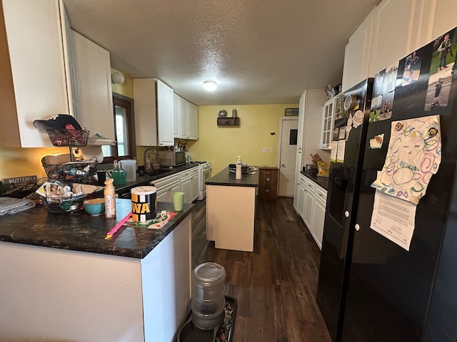 626 W Main St, Panora, IA 50216 - kitchen featuring white cabinets, a textured ceiling, stainless steel microwave, white range with gas cooktop, and dark wood finished floors