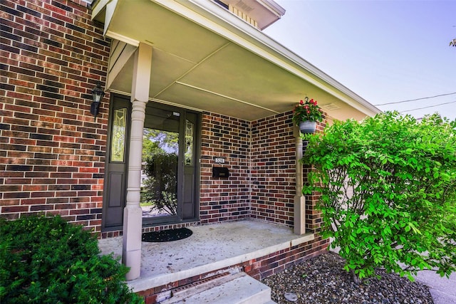 doorway to property featuring brick siding and covered porch