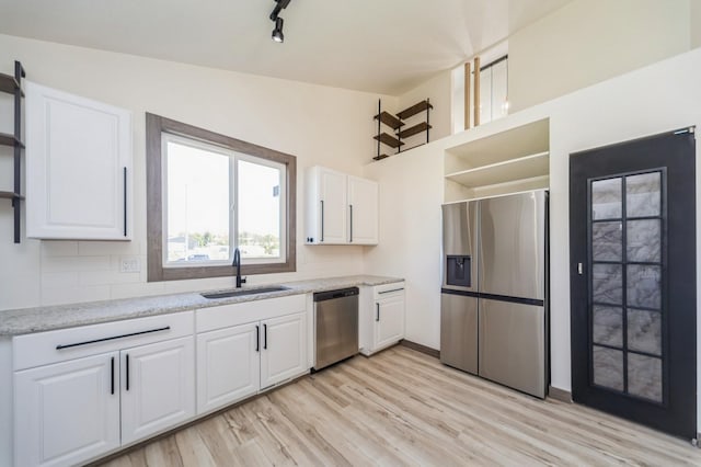 kitchen featuring appliances with stainless steel finishes, open shelves, a sink, white cabinetry, and light wood finished floors