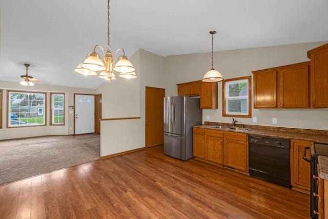 kitchen with black dishwasher, freestanding refrigerator, a sink, lofted ceiling, and brown cabinetry