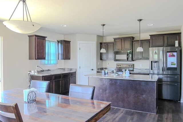4917 Richmond Ave, Des Moines, IA 50317 - kitchen featuring appliances with stainless steel finishes, dark brown cabinets, dark wood-style flooring, a kitchen island with sink, and recessed lighting