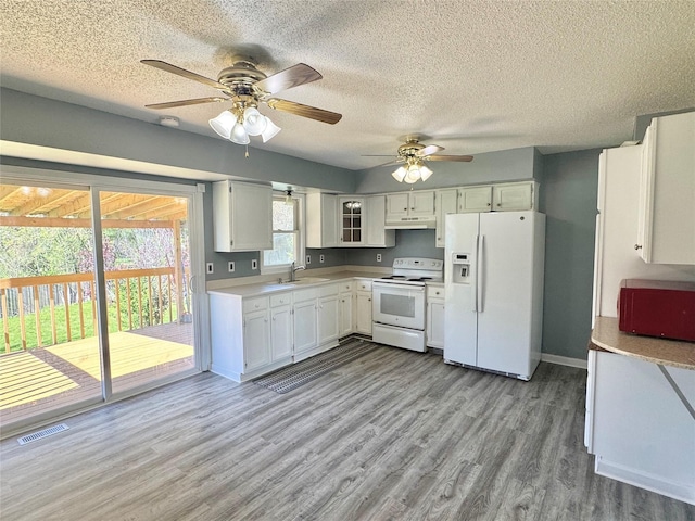 kitchen featuring white appliances, under cabinet range hood, light countertops, light wood-style flooring, and a sink