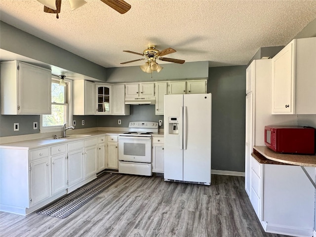 kitchen with white appliances, a sink, a ceiling fan, under cabinet range hood, and wood finished floors