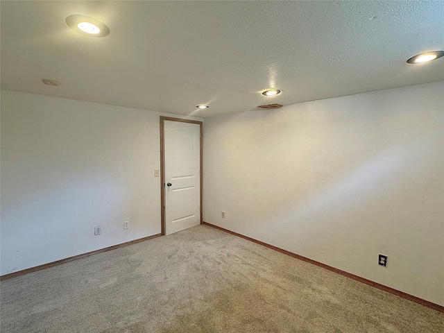 unfurnished room with light colored carpet, baseboards, and a textured ceiling