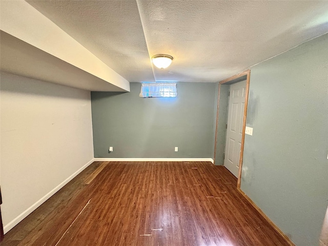 basement with wood finished floors, baseboards, and a textured ceiling
