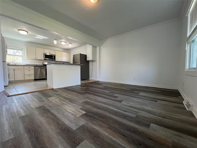 kitchen with stainless steel appliances, open floor plan, wood finished floors, crown molding, and baseboards