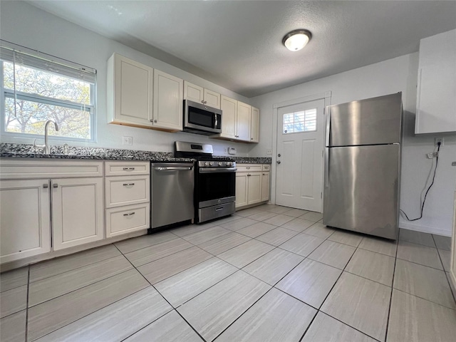 kitchen featuring stainless steel appliances, a sink, and light tile patterned floors