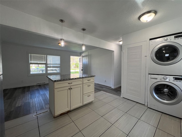 washroom featuring stacked washer and clothes dryer, light tile patterned flooring, and baseboards