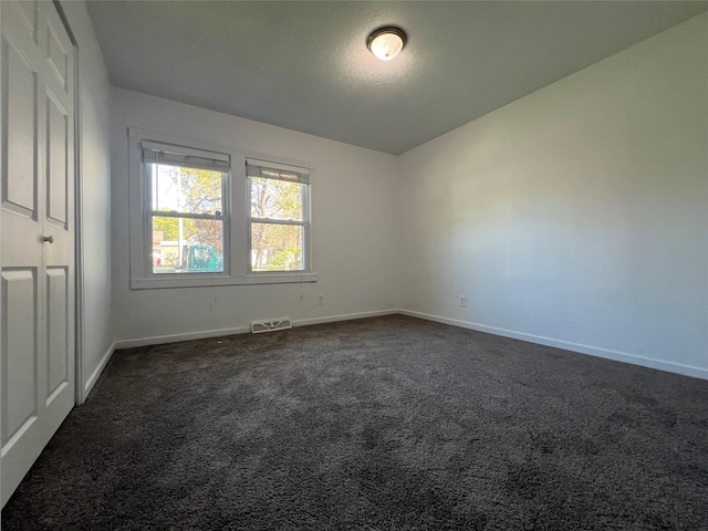unfurnished room featuring baseboards and dark colored carpet