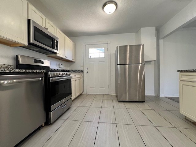 kitchen featuring appliances with stainless steel finishes, a textured ceiling, and light tile patterned flooring