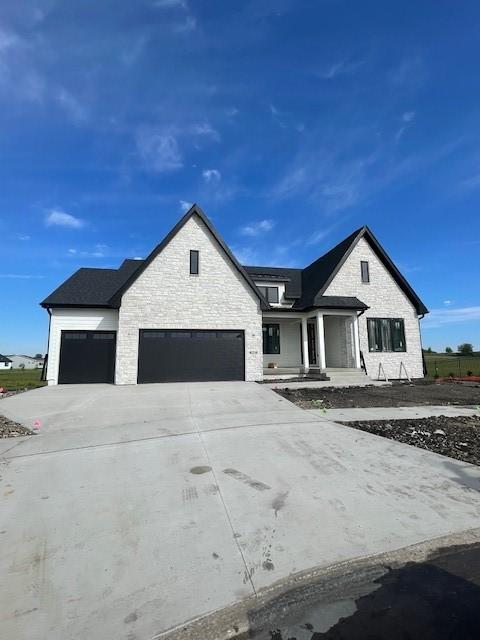 8236 Mahon Ct, Johnston, IA 50131 - modern inspired farmhouse featuring an attached garage, stone siding, driveway, and a porch