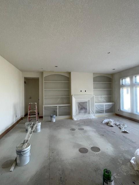 8236 Mahon Ct, Johnston, IA 50131 - unfurnished living room with a textured ceiling, built in features, and baseboards