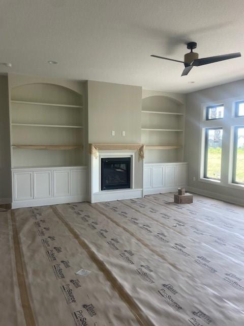 8236 Mahon Ct, Johnston, IA 50131 - unfurnished living room with built in shelves, ceiling fan, and a glass covered fireplace