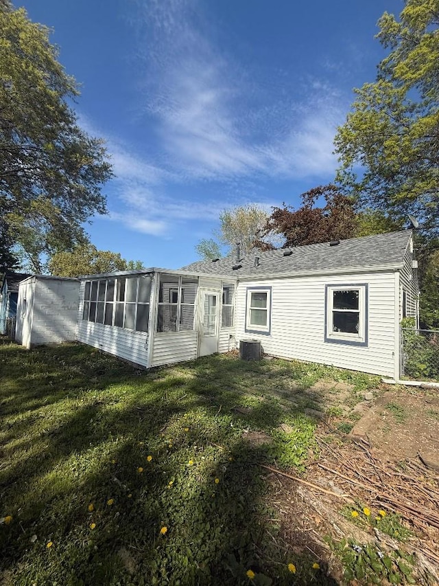 rear view of property featuring a sunroom, central air condition unit, and a yard