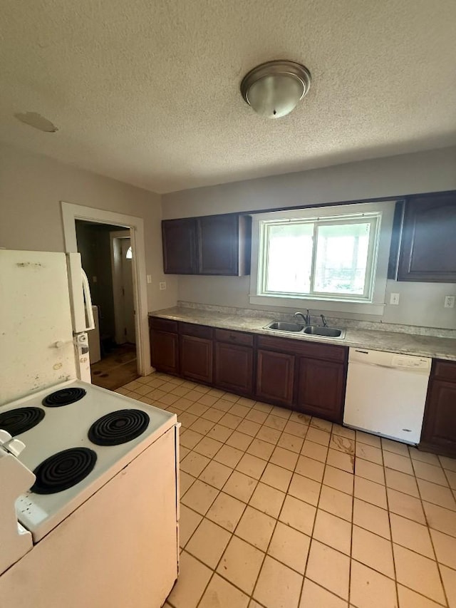kitchen with white appliances, a sink, light countertops, light tile patterned floors, and a textured ceiling