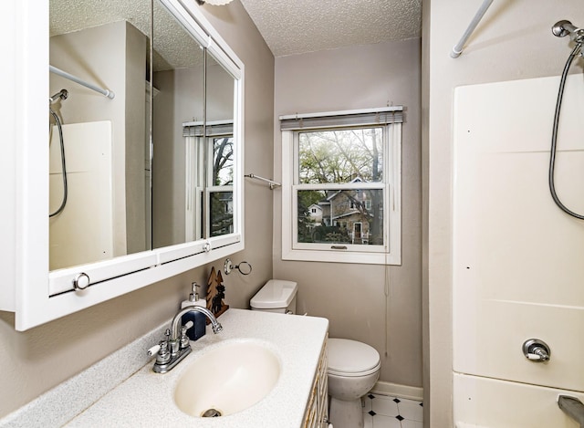 bathroom with toilet, a shower, a textured ceiling, vanity, and baseboards