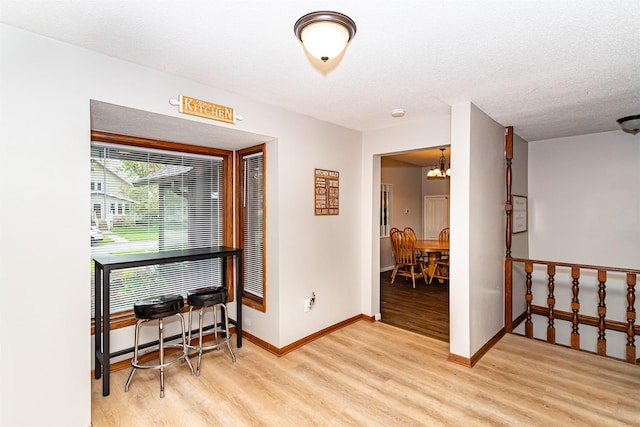 interior space with wood finished floors, a chandelier, baseboards, and a textured ceiling