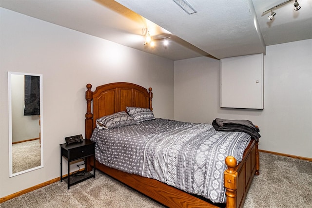 carpeted bedroom with baseboards and track lighting