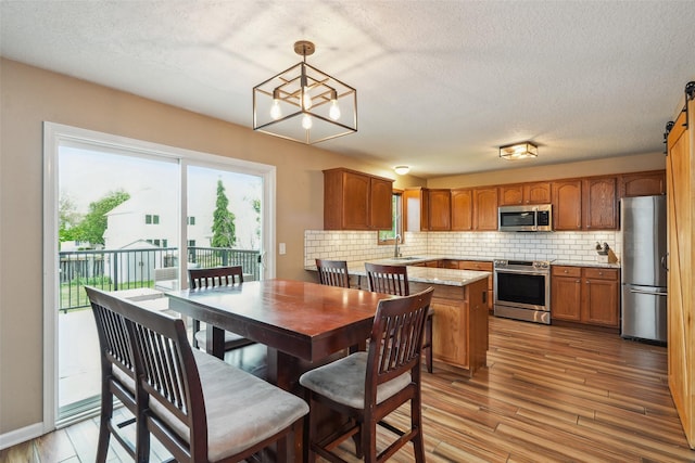 9905 Mcwilliams Dr, Johnston, IA 50131 - dining area with a barn door, light wood-style flooring, a textured ceiling, and a chandelier