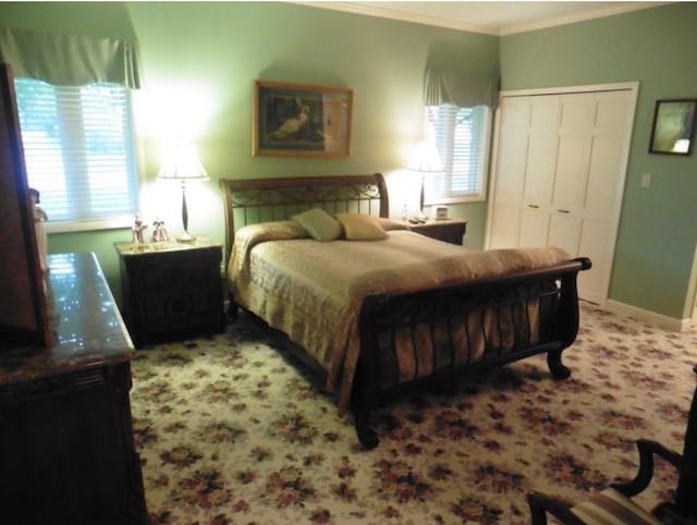 carpeted bedroom featuring ornamental molding, a closet, and baseboards