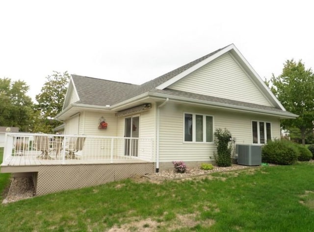 view of home's exterior with a wooden deck, central AC unit, a lawn, and roof with shingles