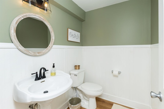 2620 35th St, Des Moines, IA 50310 - bathroom with toilet, wainscoting, wood finished floors, a decorative wall, and a sink
