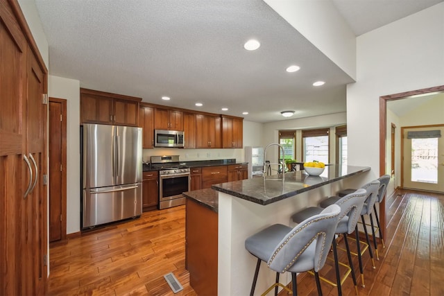 15919 Hawthorn Cir, Clive, IA 50325 - kitchen featuring stainless steel appliances, wood-type flooring, a kitchen bar, recessed lighting, and a sink