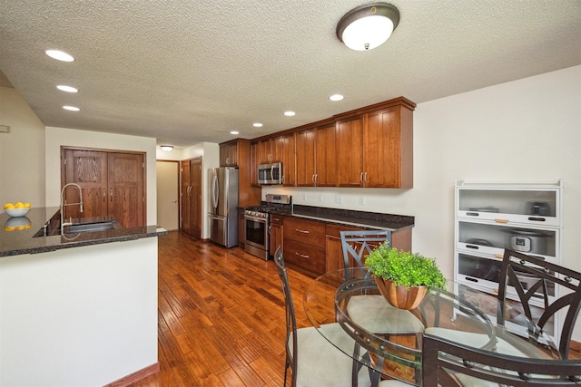 15919 Hawthorn Cir, Clive, IA 50325 - kitchen featuring appliances with stainless steel finishes, a sink, dark wood finished floors, recessed lighting, and a textured ceiling
