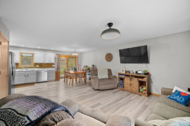 living room featuring light wood-style flooring, baseboards, recessed lighting, and a chandelier