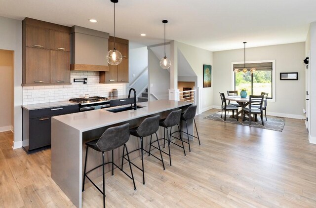 2113 NE Heritage Dr, Grimes, IA 50111 - kitchen with stainless steel gas stove, decorative backsplash, a breakfast bar, light wood-type flooring, and recessed lighting