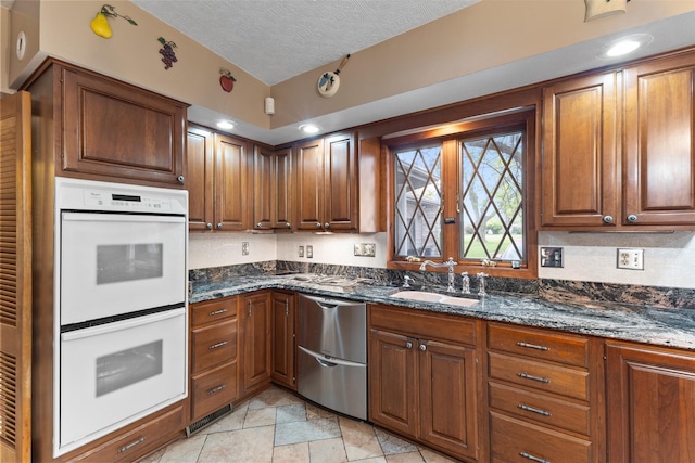 1608 W Lincoln Way, Marshalltown, IA 50158 - kitchen with white double oven, stainless steel dishwasher, a sink, dark stone countertops, and a textured ceiling