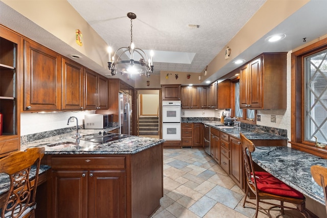 1608 W Lincoln Way, Marshalltown, IA 50158 - kitchen featuring appliances with stainless steel finishes, a chandelier, a peninsula, a sink, and a textured ceiling