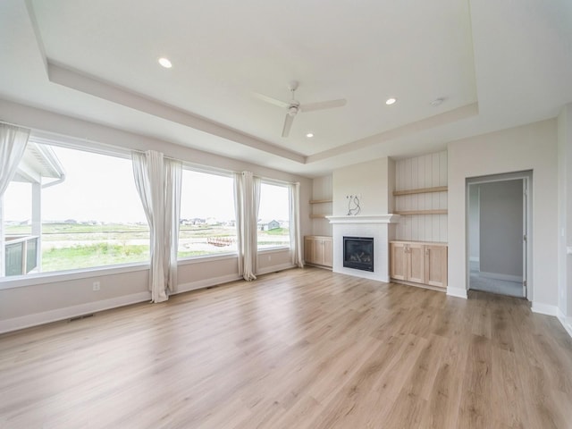 460 NW Gracewood Dr, Waukee, IA 50263 - unfurnished living room featuring a tray ceiling, plenty of natural light, light wood-type flooring, and recessed lighting