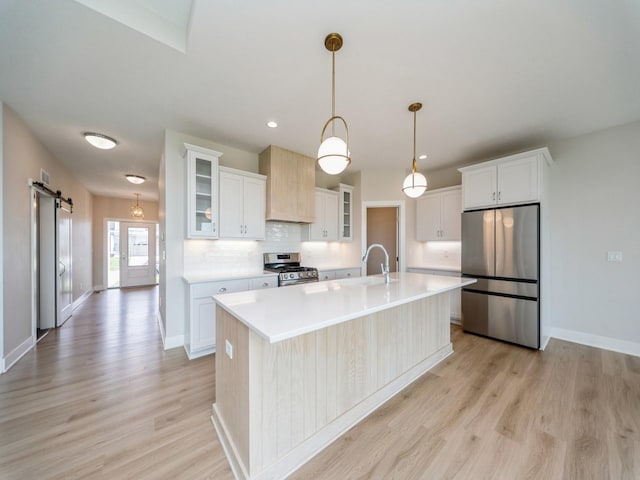 460 NW Gracewood Dr, Waukee, IA 50263 - kitchen with stainless steel appliances, a barn door, light wood-style floors, light countertops, and white cabinetry