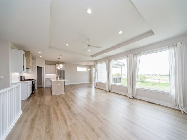 460 NW Gracewood Dr, Waukee, IA 50263 - unfurnished living room with a tray ceiling, ceiling fan, recessed lighting, baseboards, and light wood-style flooring