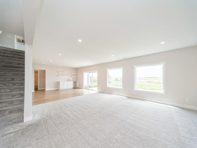 460 NW Gracewood Dr, Waukee, IA 50263 - unfurnished living room with light colored carpet, stairs, baseboards, and recessed lighting