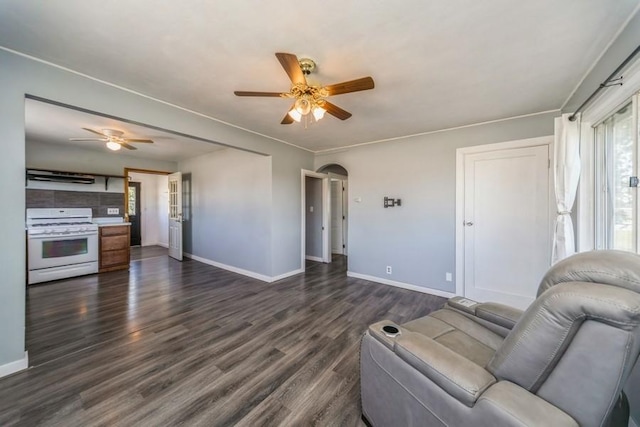 living area featuring a ceiling fan, baseboards, arched walkways, and dark wood-type flooring