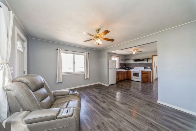 living area with baseboards, ceiling fan, and dark wood-style flooring