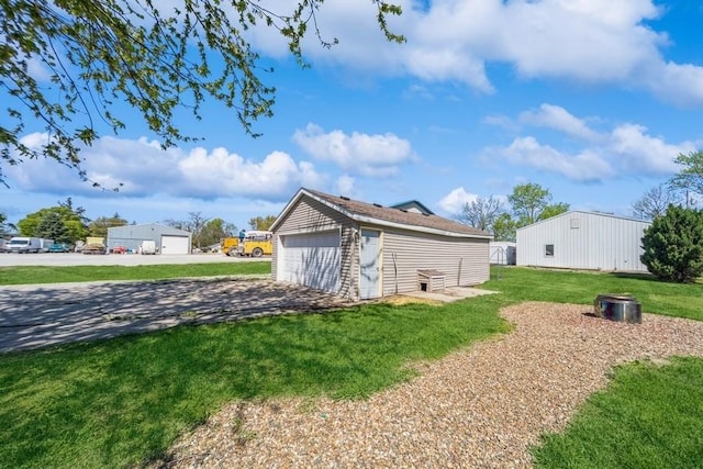 view of green lawn with an outdoor structure and a garage
