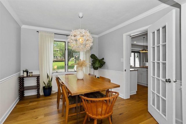 7422 Plum Dr, Urbandale, IA 50322 - dining space with a chandelier, light wood-style floors, ornamental molding, and baseboards