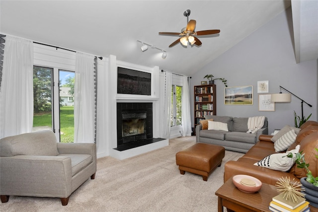 7422 Plum Dr, Urbandale, IA 50322 - living room with a ceiling fan, carpet floors, vaulted ceiling, a tile fireplace, and track lighting