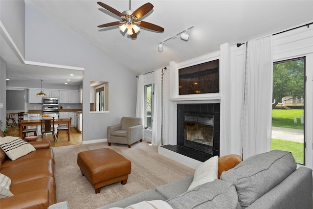 7422 Plum Dr, Urbandale, IA 50322 - living room with a ceiling fan, a tiled fireplace, plenty of natural light, track lighting, and high vaulted ceiling