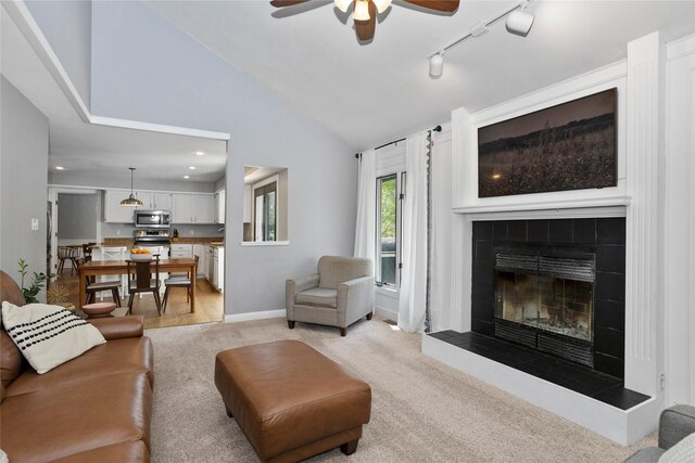 7422 Plum Dr, Urbandale, IA 50322 - living room featuring ceiling fan, light colored carpet, a fireplace, baseboards, and rail lighting