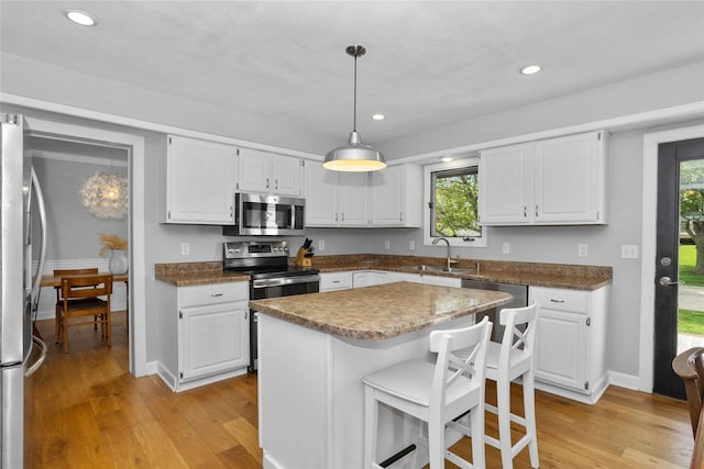 7422 Plum Dr, Urbandale, IA 50322 - kitchen with stainless steel appliances, a sink, light wood finished floors, white cabinetry, and recessed lighting